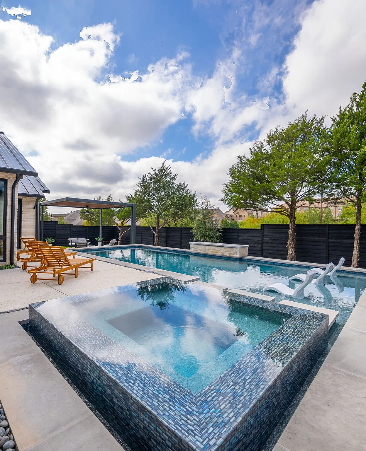 Custom pool with raised spa and tanning ledge by Verde Outdoors