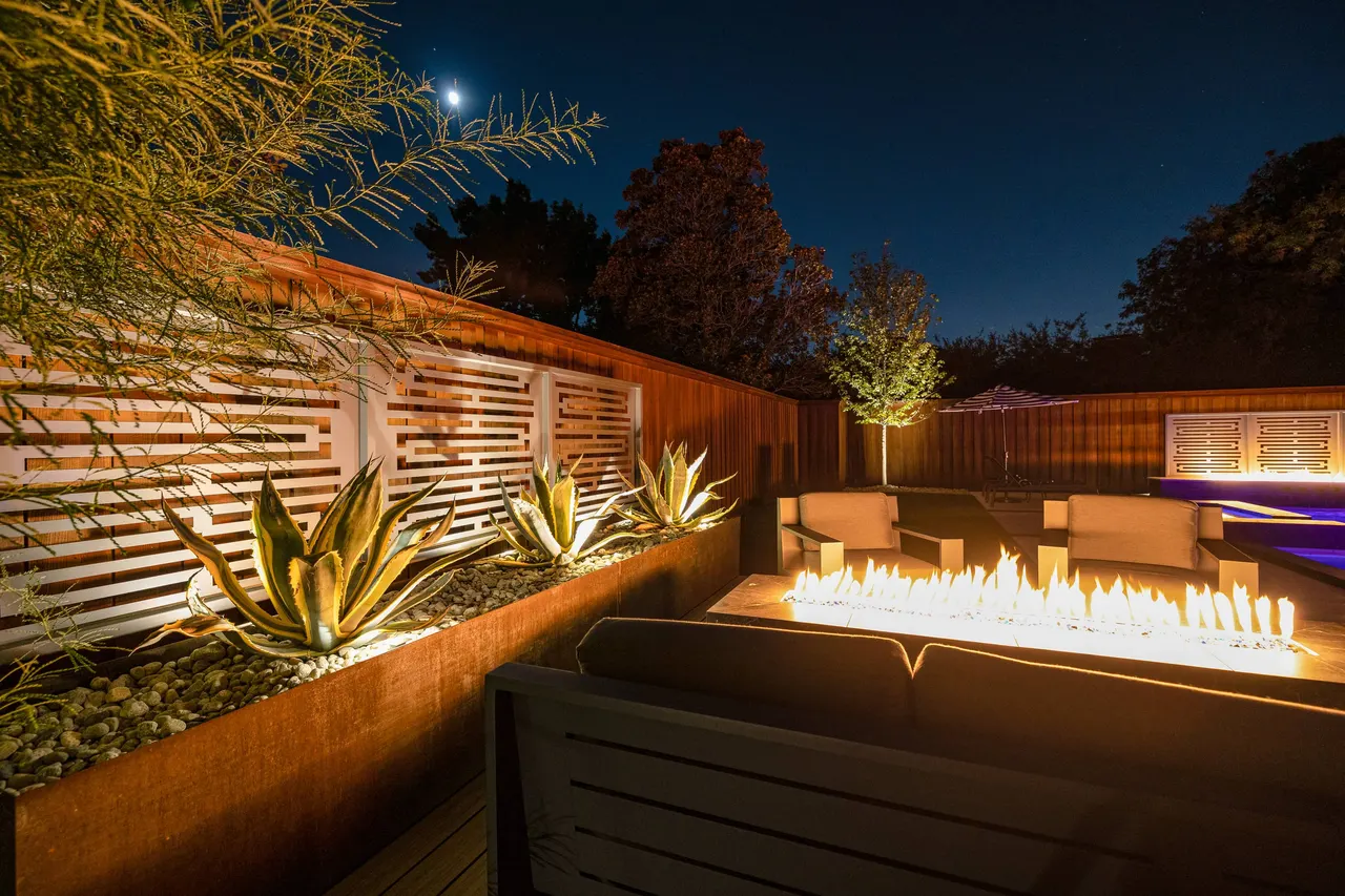 Linear fire feature and slatted privacy wall in a custom backyard