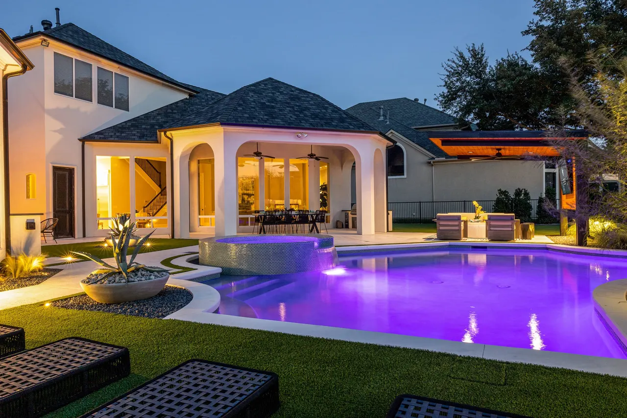 Luxury backyard pool with cabana lit at dusk